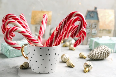 Many sweet candy canes in cup on light table. Traditional Christmas treat