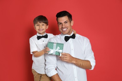 Man receiving gift for Father's Day from his son on red background