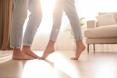 Couple dancing barefoot at home, closeup. Floor heating system