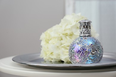 Stylish catalytic lamp with hydrangea on table in room closeup. Cozy interior