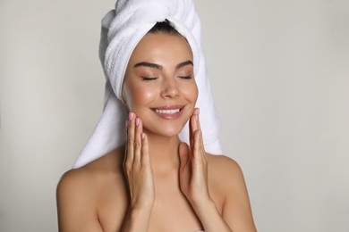 Photo of Beautiful young woman with towel on head against light background