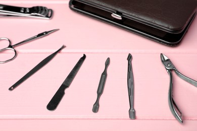 Manicure set and case on pink wooden background