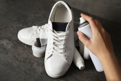 Woman cleaning stylish footwear on dark grey background, closeup. Shoe care accessories