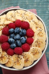 Tasty breakfast dish with berries, banana and chia seeds on wooden table, top view