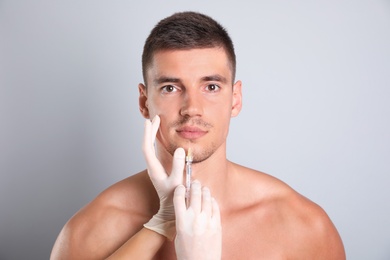 Man getting facial injection on grey background. Cosmetic surgery