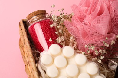 Spa gift set of different luxury products in wicker basket on pale pink background, closeup