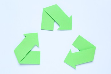 Recycling symbol made of green paper arrows on white background, top view