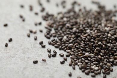 Photo of Pile of chia seeds on light grey table, closeup. Space for text