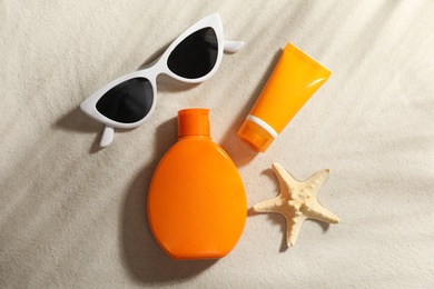 Flat lay composition with sun protection cosmetic products on sand