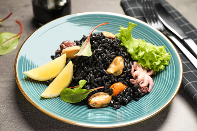 Photo of Delicious black risotto with seafood and lemon on plate