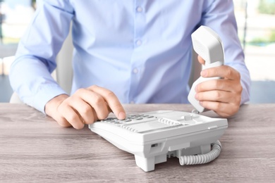 Man dialing number on telephone at workplace