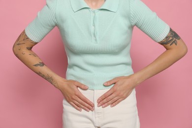 Photo of Young woman suffering from menstrual pain on pink background, closeup