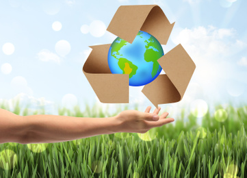 Man with illustration of Earth and recycling symbol in hand, closeup