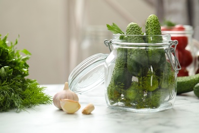 Pickling jar with fresh cucumbers on white marble table