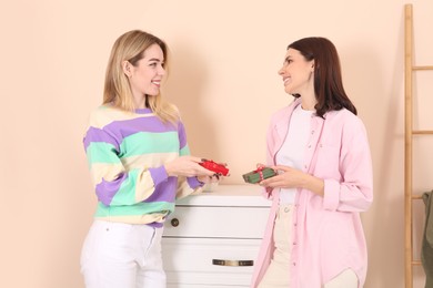 Photo of Smiling young women presenting gifts to each other indoors