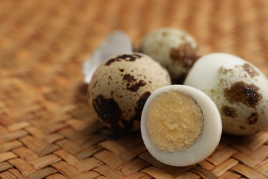 Photo of Unpeeled and peeled hard boiled quail eggs on wicker surface, closeup