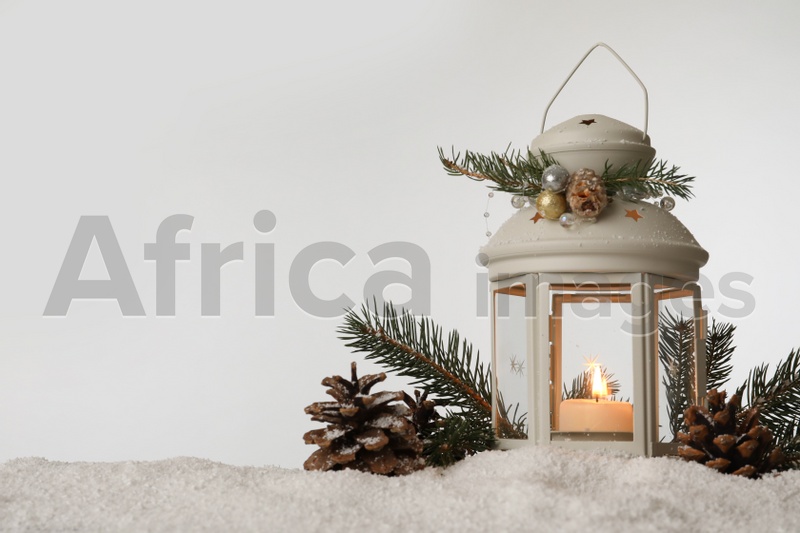 Decorative lantern and Christmas decor on snow against light grey background. Space for text