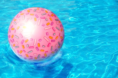 Inflatable beach ball floating in swimming pool 