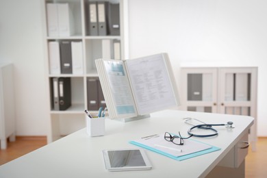 Doctor's workplace with tablet and stationery in medical office