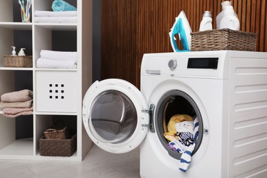 Laundry room interior with washing machine near wooden wall