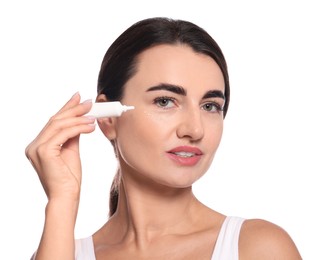 Woman with cosmetic product around eye on white background. Skin care