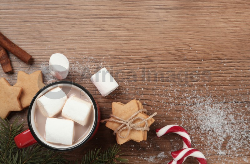 Flat lay composition with marshmallows, hot drink and sweets on wooden table. Space for text