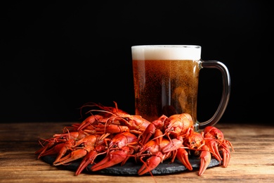 Delicious red boiled crayfishes and mug of beer on wooden table