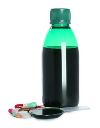 Bottle of cough syrup, dosing spoon and pills on white background