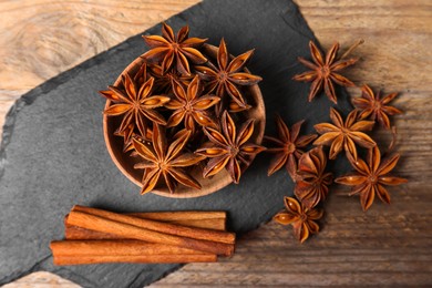 Aromatic cinnamon sticks and anise stars on wooden table, flat lay