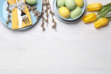 Festive Easter table setting with eggs on white wooden background, flat lay. Space for text