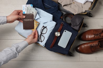 Man packing suitcase for business trip on wooden floor, top view