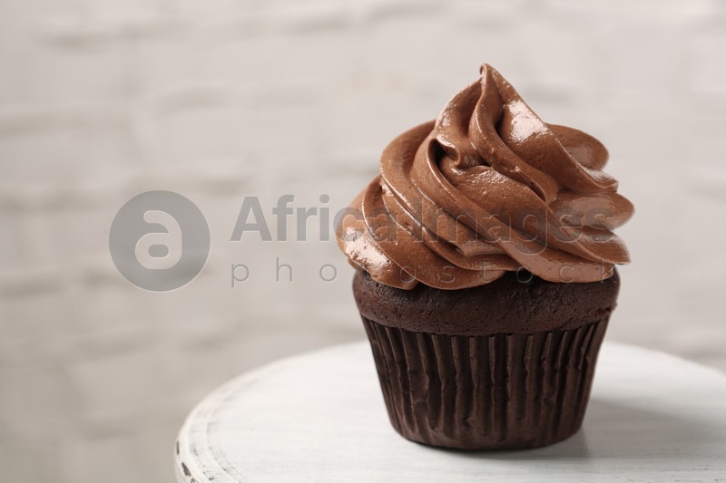 Photo of Delicious chocolate cupcake with cream on white table, closeup. Space for text