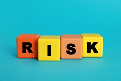 Word Risk made of colorful cubes on turquoise background