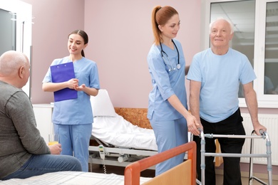Nurses with senior patients in hospital ward. Medical assisting
