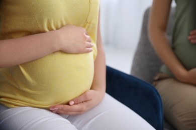 Pregnant woman sitting on chair indoors, closeup. Courses for expectant mothers