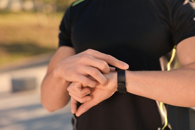 Man checking pulse after training outdoors, closeup. Space for text