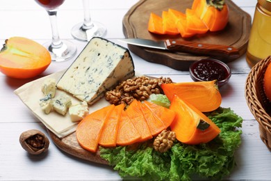 Photo of Delicious persimmon, blue cheese and nuts served on white wooden table