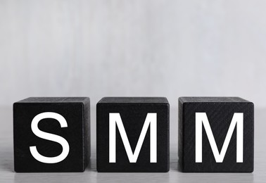 Cubes with abbreviation SMM (Social media marketing) on light grey background
