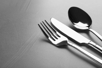 Shiny cutlery on grey table, closeup. Space for text