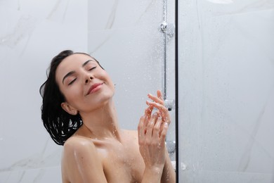 Beautiful young woman taking shower at home