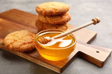 Tasty honey and cookies on light grey table