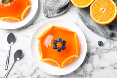 Delicious fresh jelly with orange slices and blueberries on marble table, flat lay