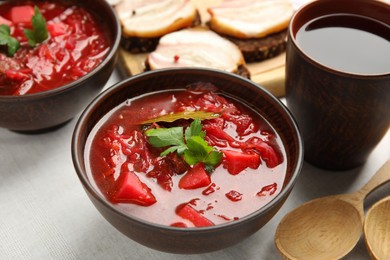 Stylish brown clay bowl with Ukrainian borsch served on white tablecloth