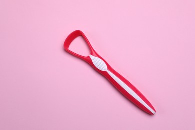 Red tongue cleaner on pink background, top view