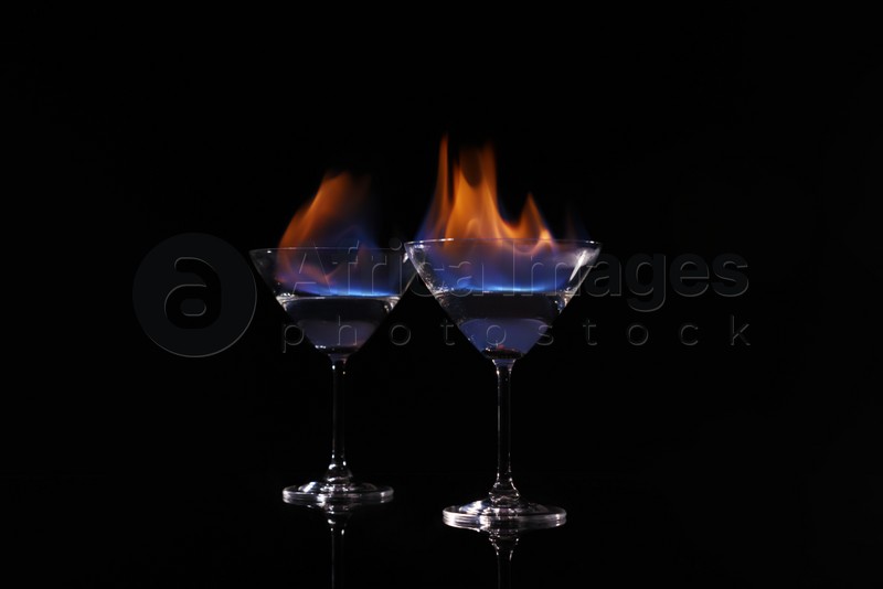 Cocktail glasses with flaming vodka on black background
