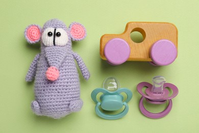 Photo of Flat lay composition with pacifiers and other baby stuff on pale green background