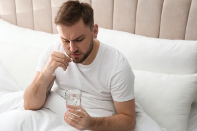 Man taking pill against migraine in bed