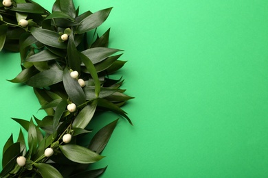 Beautiful handmade mistletoe wreath on green background, top view. Space for text