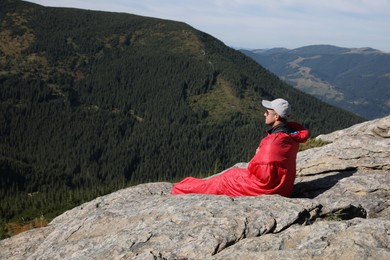 Tourist in sleeping bag on mountain peak