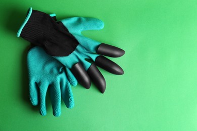 Gardening gloves on green background, top view. Space for text